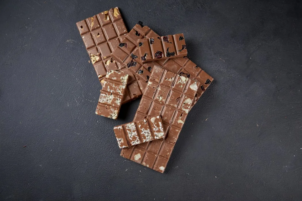Barras de chocolate DONUTRI quebradas sobre uma placa de chocolate com o monograma da marca
